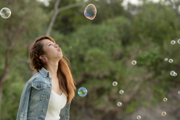 istock Young female having fun and blowing bubbles outdoors 821832784