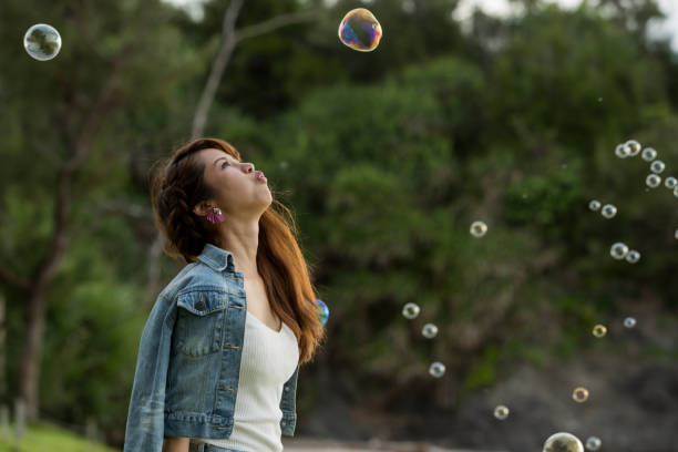 istock Young female having fun and blowing bubbles outdoors 821832792