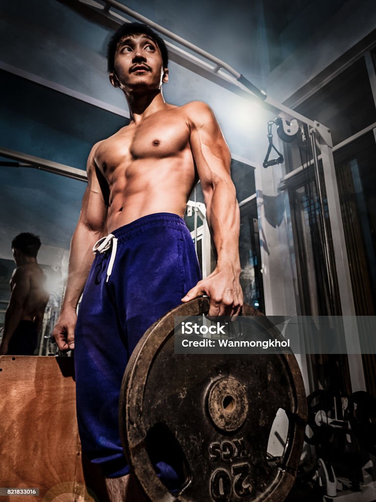 亞洲健美健身喬裝與他的完美的肌肉和身體線條後在家裡杠鈴鍛煉健身 - 免版稅一個人圖庫照片