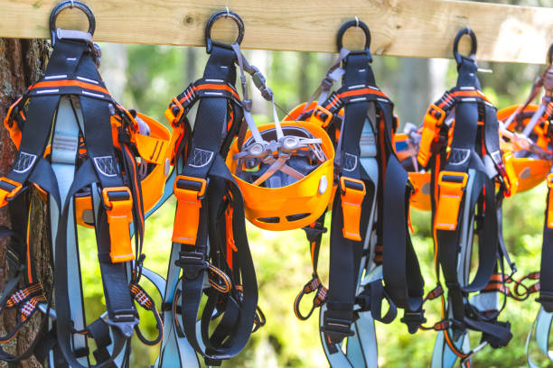 klettern ausrüstung ausrüstung - orange helm kabelbaum zip line sicherheitsausrüstung hängend auf einem brett. - zip lining stock-fotos und bilder