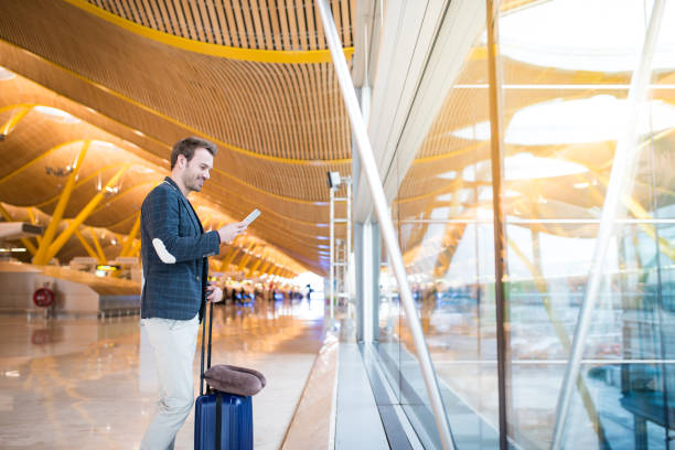 istock man using mobile phone at the airport looking trough the window 821836876