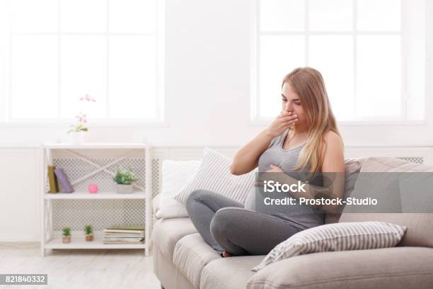 Young Vomiting Woman Sitting On Sofa Stock Photo - Download Image Now - Pregnant, Morning Sickness, Vomit