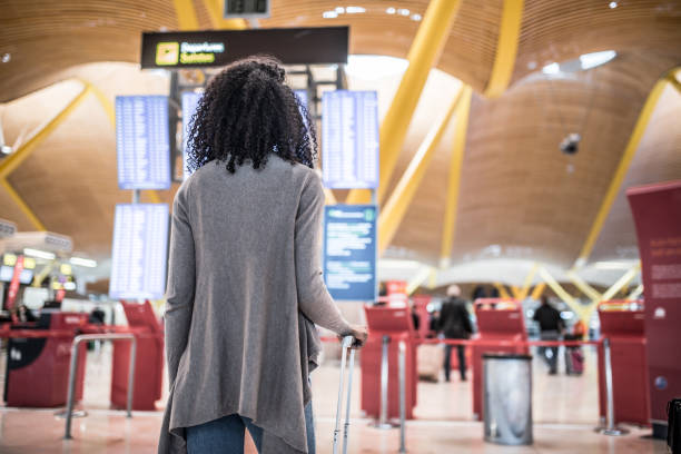 istock Woman looking at the timetable information panel in the airport with a suitcase 821840574