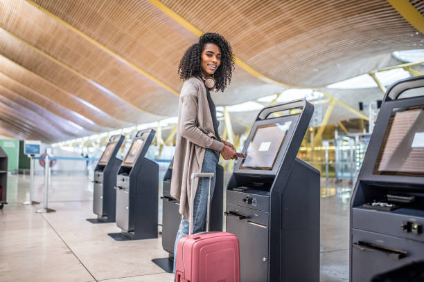 istock happy woman using the check-in machine at the airport getting the boarding pass. 821840596