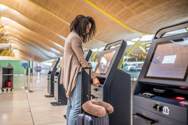 istock happy woman using the check-in machine at the airport getting the boarding pass. 821840612