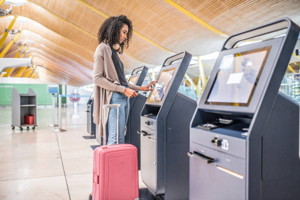 mujer negra feliz usando la máquina de check-in en el aeropuerto para el embarque. - área de embarque fotografías e imágenes de stock