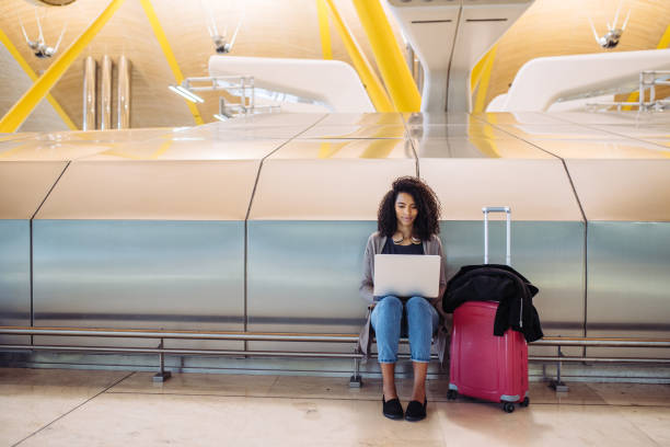 attractive black Woman at the airport sitting and working with laptop stock photo