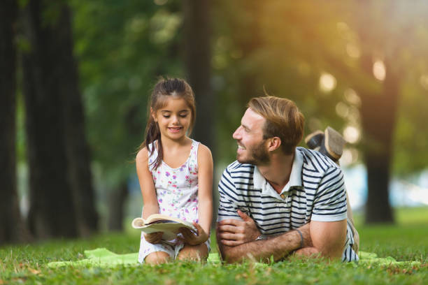 istock Father and daughter reading a book in the park 821842516