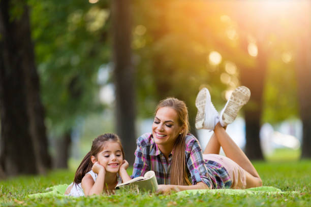 istock Mother and daughter reading book in a park 821845608