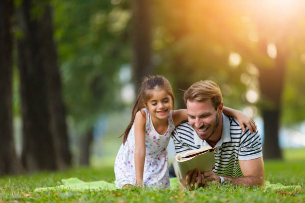 istock Father and daughter reading a book in the park 821848988