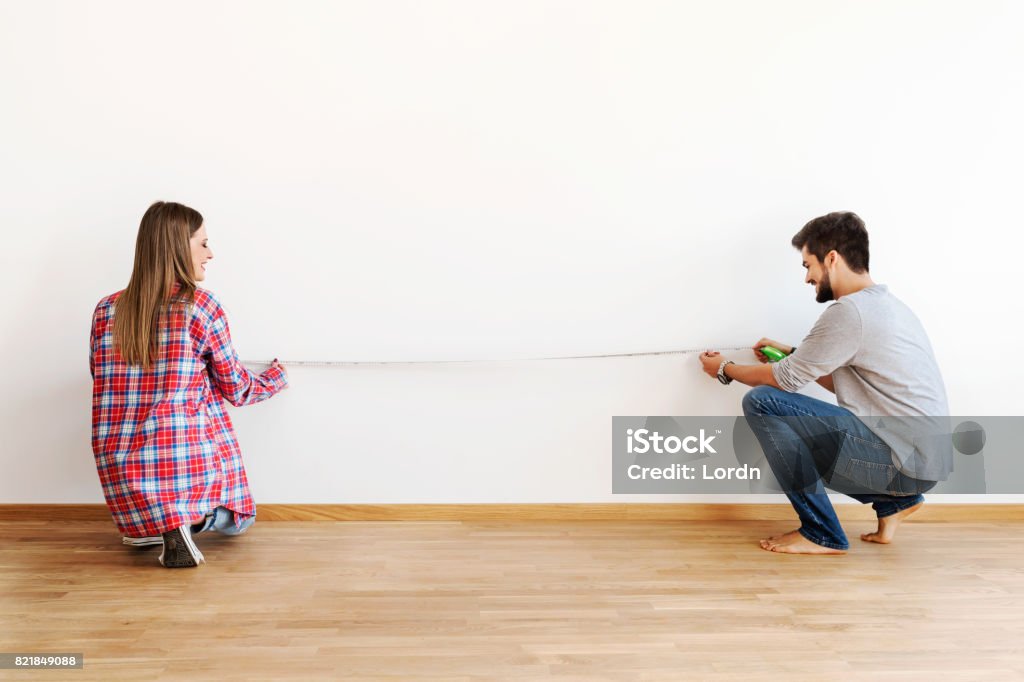 Couple in empty apartment measuring walls Measuring Stock Photo