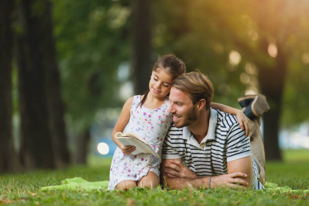 istock Father and daughter reading a book in the park 821851876
