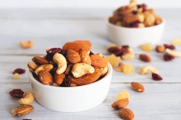 mixed nuts and dried fruit mixed nuts and dried fruit in wooden bowl on wooden table top view. Walnut, pistachio, almond, hazelnut, cashews, apricot, berry, banana, pineapple, Healthy food and snack nut stock pictures, royalty-free photos & images