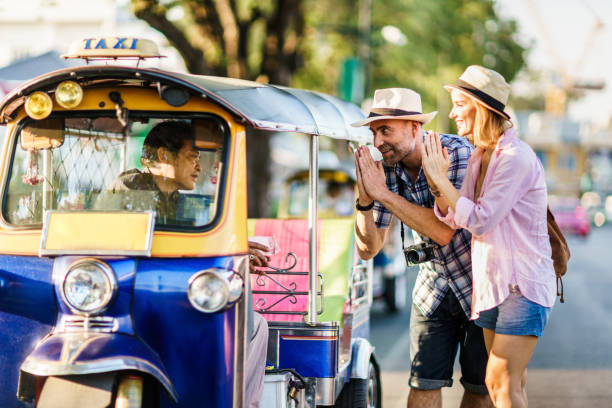 Middle-aged man and his companion handsome blond lady on a tuk-tuk ride in Bangkok stock photo