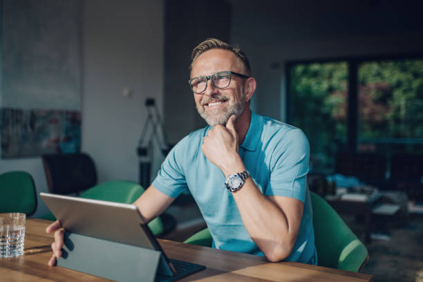 istock smiling midaged man with glasses at table with tablet 821859772
