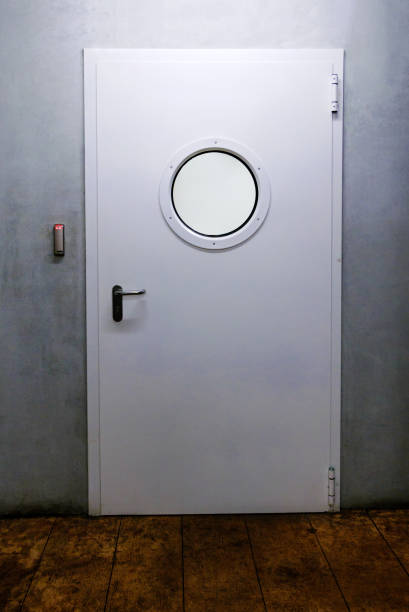 Ship door with porthole and industrial environment.
