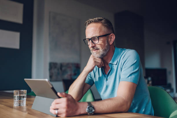 istock bearded midaged man with glasses at table with tablet 821860368