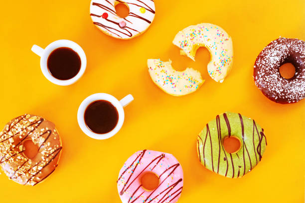 istock Variety of donuts and coffee on yellow table. 821868792