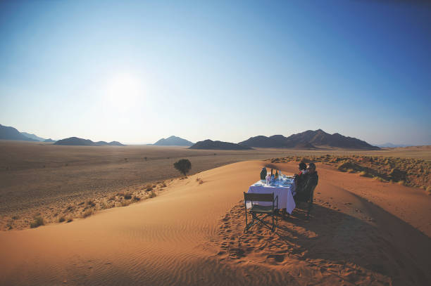 Dune Breakfast Coffee Scene A man and woman sitting at an outdoor picnic table having coffee and breakfast on a sand dune Namib Rand Namibian Desert Namibia Africa wonderlust stock pictures, royalty-free photos & images