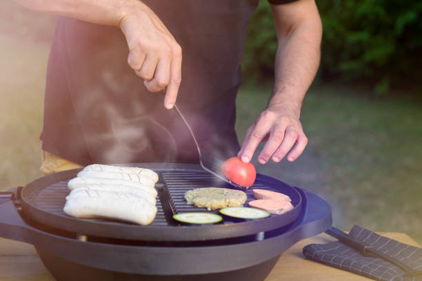 Unrecognisable man using electric grill. Garden grill party concept