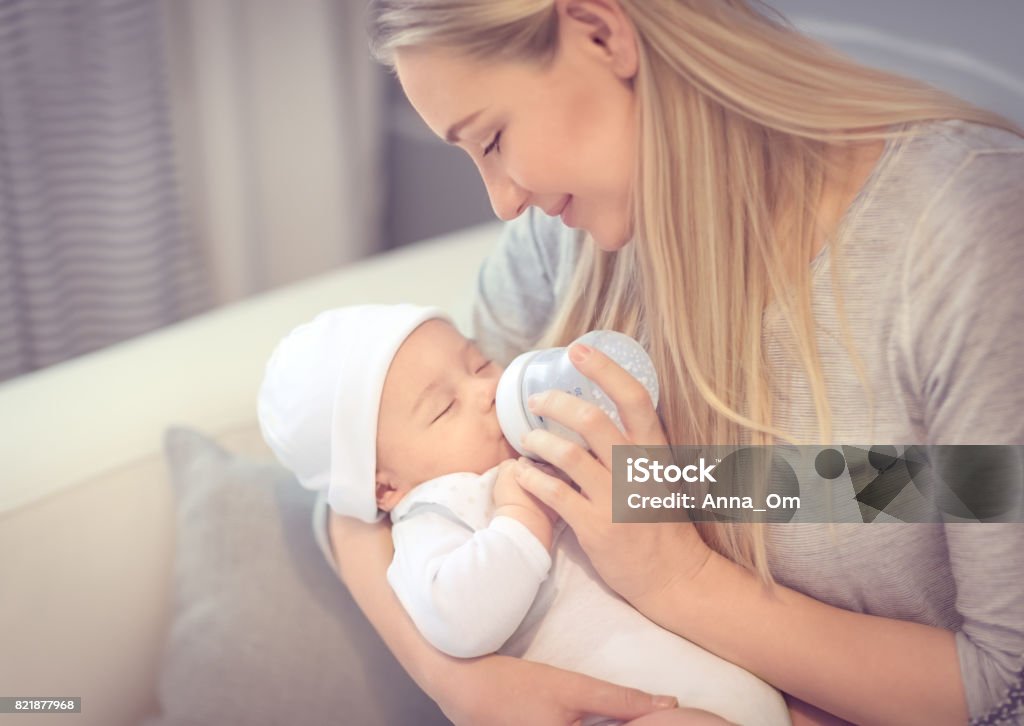 Jeune mère nourrit son bébé précieux petit - Photo de Bouteille libre de droits