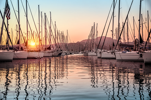 Beautiful sailboats moored in the dock, amazing view of gorgeous white sail boats over mountains background in mild sunset light, luxury summer vacation in Marmaris, Turkey