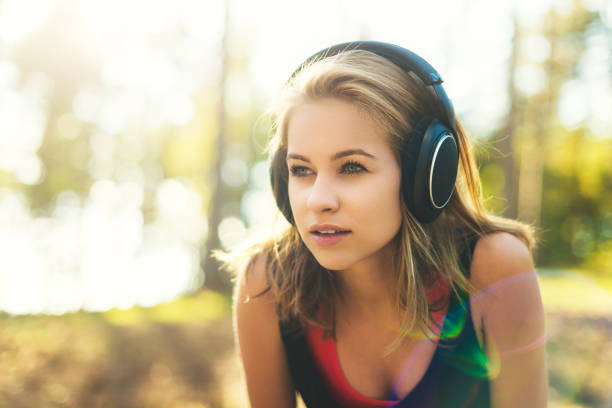 jovem desportista atraente ouvir música usando fones de ouvido. - distance running audio - fotografias e filmes do acervo