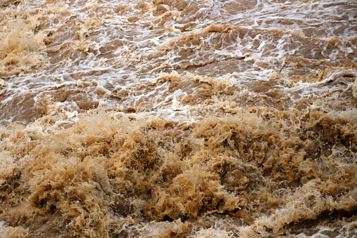 Red turbid water flows down from the mountain due to torrential rain.