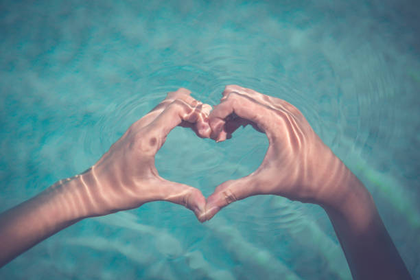 istock Female making heart shape with hands in water 821888868