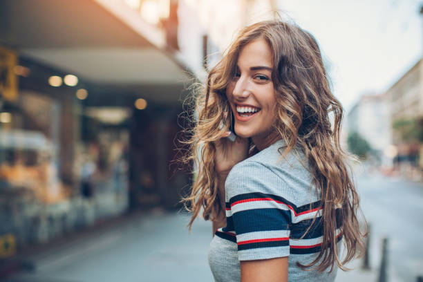 Cheerful woman walking on the street and talking on the phone, looking over her shoulder