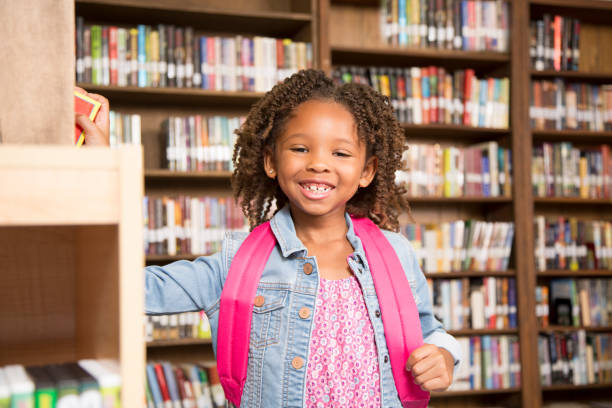 istock African descent little girl in school library choosing book. 821889466