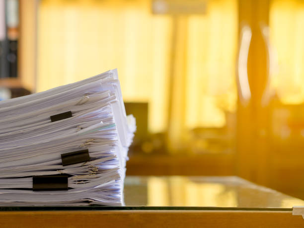 istock Stack of paper files on work desk in office. Flare light. 821894132