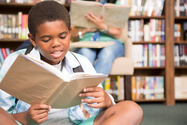 istock African descent boy in school library with book. 821894300