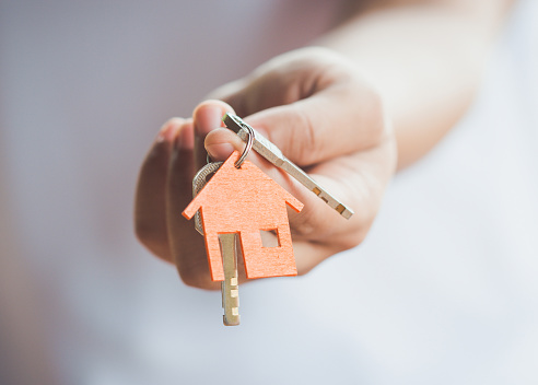 Female hand holding keys with house key,real estate agent.