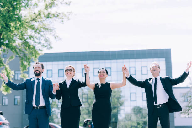 istock triumphing multiethnic businesspeople holding hands while standing together outside 821899094