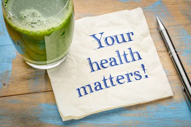 our health matters reminder or advice - handwriting on a napkin with a glass of fresh, green, vegetable juice