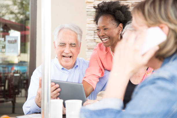 istock Multi-ethnic group of senior adult friends using digital tablet at cafe. 821904598