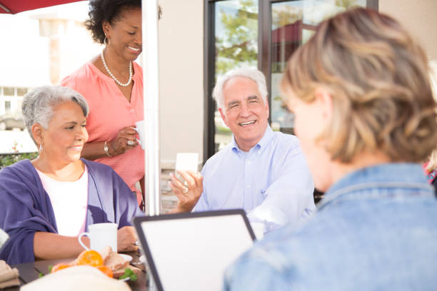 istock Multi-ethnic group of senior adult friends using technology at cafe. 821910326