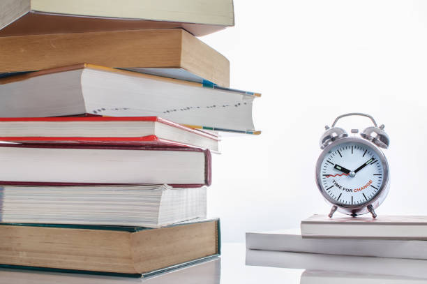 istock Stack of textbook with time to change words on alarm clock 821911890
