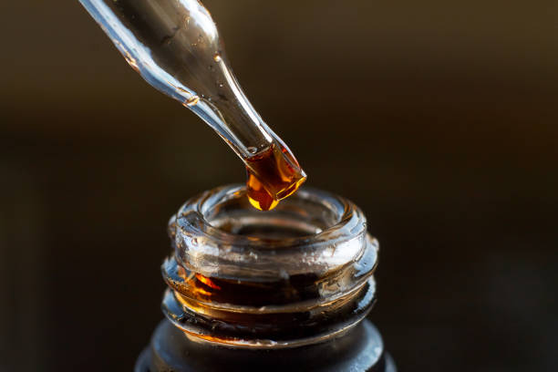 istock Pipette with drop on a black glass bottle 821912518