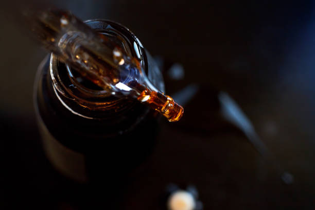istock Pipette with drop on a black glass bottle 821912966