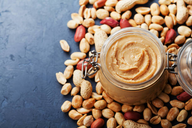 istock Peanut butter jar and heap of nuts on vintage table with copy space for text. 821927766