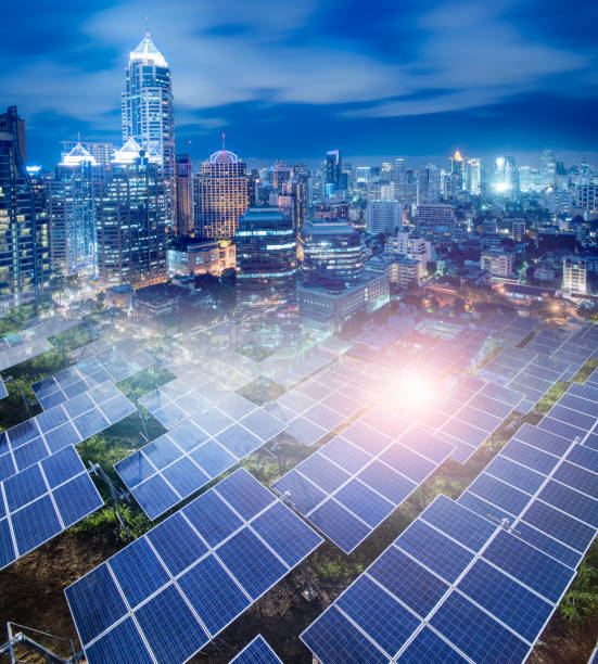 Solar Panels (solar cell) in solar farm and  The Modern City panorama  background at night. stock photo