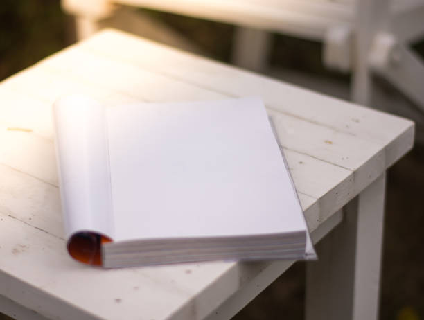 istock Close up the white book on the table in garden with sun light 821937474