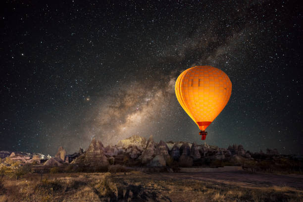 Hot air balloon flying over spectacular Cappadocia under the sky with milky way and shininng star at night stock photo