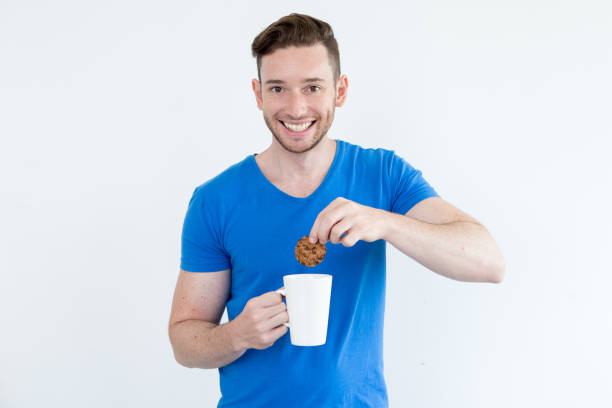 istock Happy man immersing cookie into warm beverage 821946028