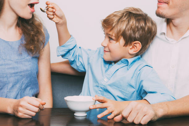 istock Cheerful boy feeding young mother with porridge 821962478