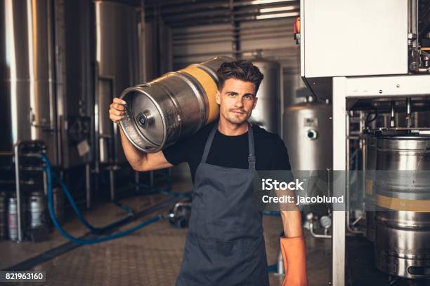 Male Brewer Carrying Metal Container At Brewery Factory Stock Photo - Download Image Now