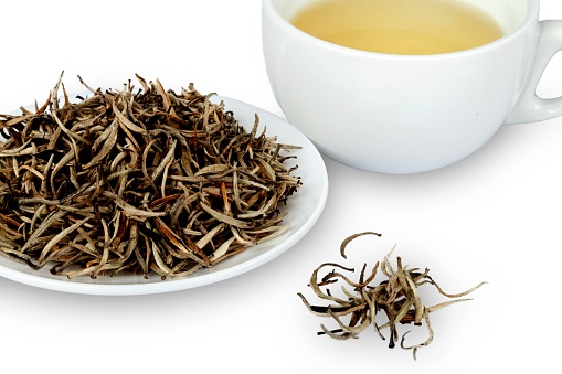 Cup of White Tea and Saucer with Dried White Tea Leaves - Top View
