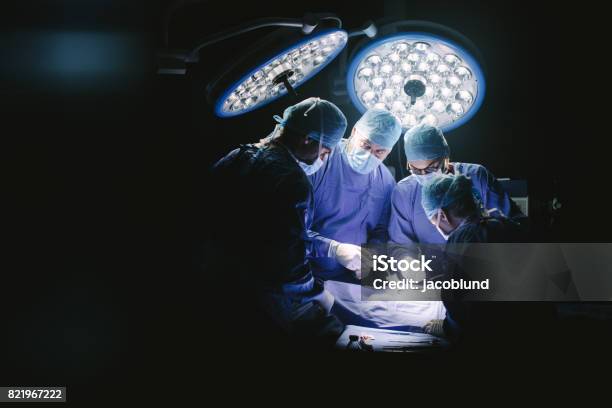 Group Of Surgeons In Hospital Operating Theater Stock Photo - Download Image Now - Surgeon, Surgery, Operating Room